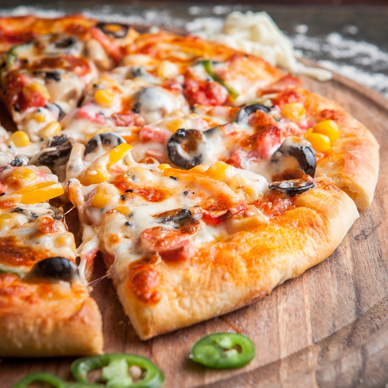 Side view pizza with chopped pepper in board cookware on dark background